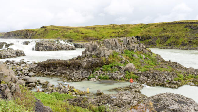 Яскравий турист перетинає білу водну річку в Ісландії. — стокове фото