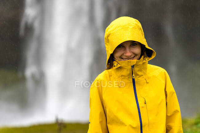Young female hiker is hiding under the hood from heavy summer rain — Stock Photo
