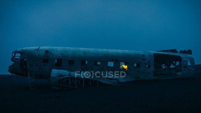 Caminhante em visão de avião abandonado na Islândia à noite. — Fotografia de Stock