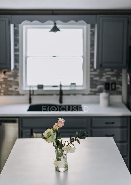 Weiße Küchenarbeitsplatte mit Blumen und Vase und Fenster im Hintergrund — Stockfoto
