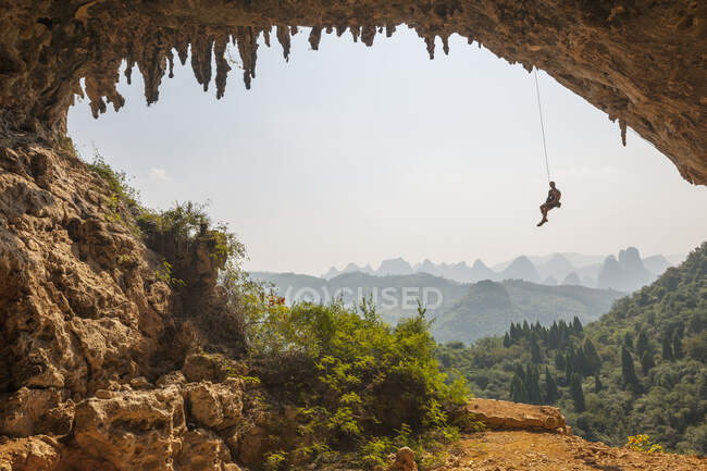 Uomo che sale l'arco al Den di Odino vicino alla collina della Luna a Yangshuo — Foto stock