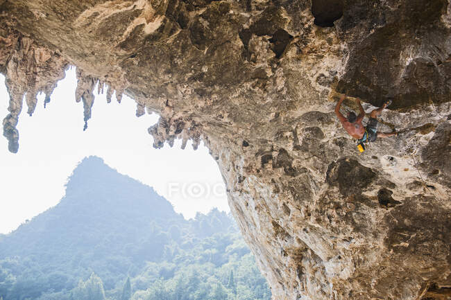 Homem escalando o arco em Odin 's Den ao lado de Moon Hill em Yangshuo — Fotografia de Stock