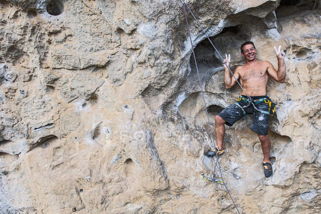 Homem sorrindo para o fotógrafo enquanto escalava no rosto de rocha na China — Fotografia de Stock