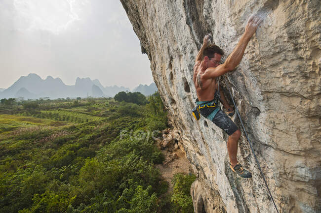 Uomo arrampicata parete di roccia in Yangshuo / Cina — Foto stock