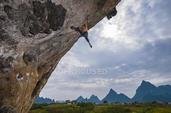 Hombre escalando voladizo empinado en Yangshuo / China - foto de stock