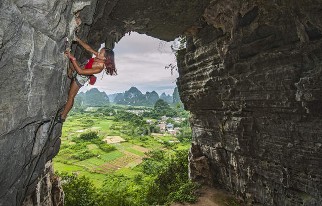 Young female climber climbing at treasure cave in Yangshuo, China — Stock Photo