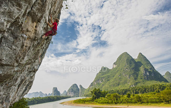 Молодой человек карабкается по крутой скале в Яншо / Китай — стоковое фото