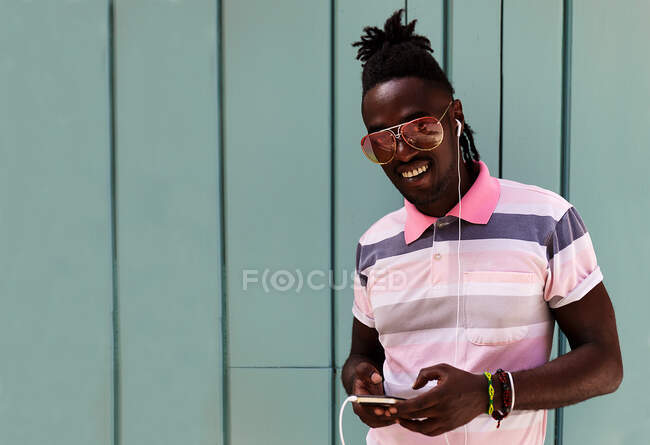 Joven cubano con trenzas afro conectadas a su móvil - foto de stock