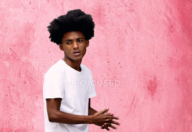 Привабливий молодий чорний чоловік, що йде перед рожевою стіною, куб — стокове фото