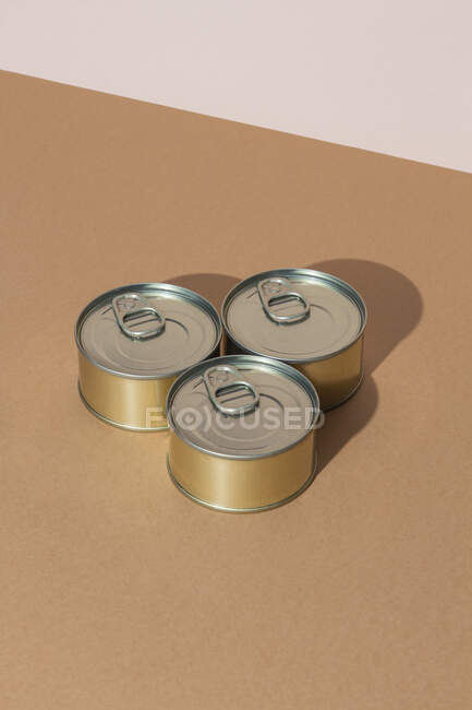 From above bunch of sealed cans with preserved food placed on brown surface — Stock Photo