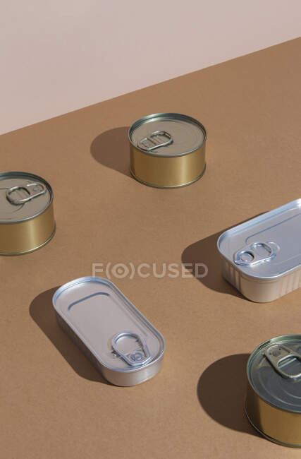 From above sealed aluminium tins of assorted canned food placed on brown surface — Stock Photo