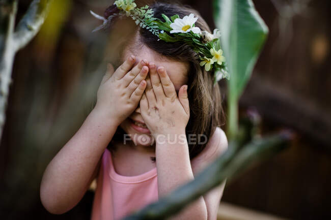 Giovane ragazza con fiore corona che copre gli occhi — Foto stock