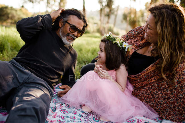 Aunt, uncle and niece sitting on blanket in field — Stock Photo