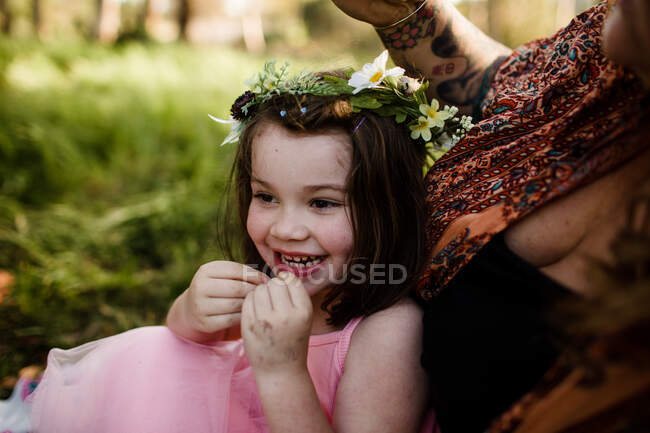 Giovane ragazza in fiore corona seduta in campo sorridente — Foto stock