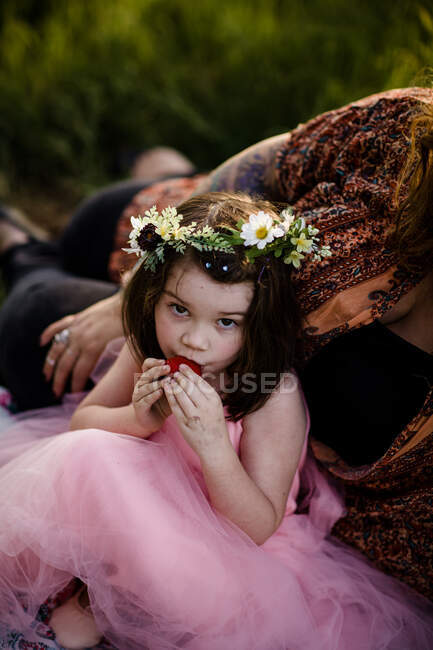 Chica joven en corona de flores posando con fresa - foto de stock