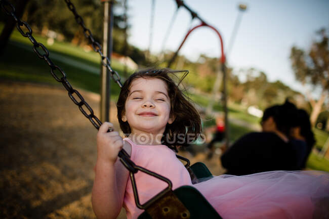 Молодая девушка на качелях, закрывая глаза и улыбаясь — стоковое фото