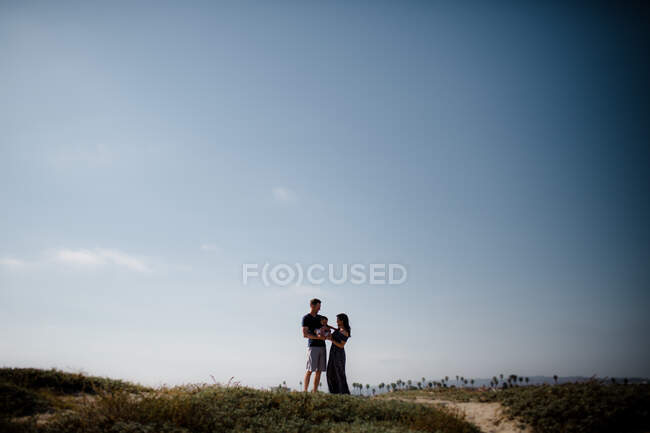 Мать и отец держат молодого солнца на пляже, силуэт — стоковое фото
