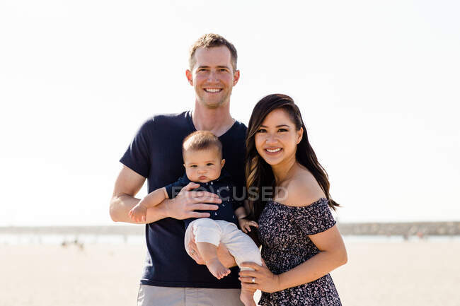 Pais jovens com menino na praia — Fotografia de Stock