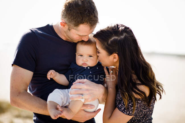 Padres jóvenes con bebé en la playa - foto de stock