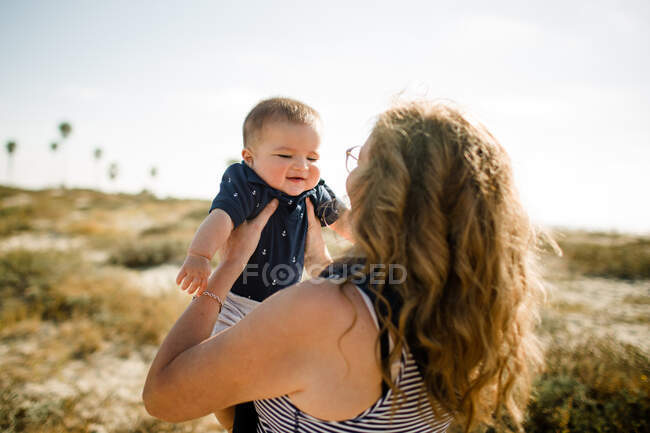 Nonna Holding nipote mentre in piedi sulla spiaggia — Foto stock