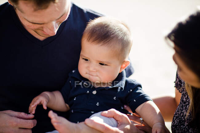 Primer plano del bebé mientras mamá y papá miran - foto de stock