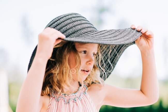 Портрет молодой девушки, улыбающейся на улице в большой шляпе — стоковое фото