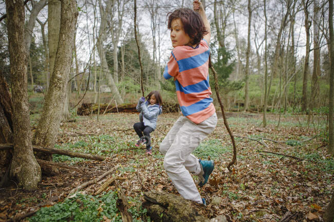 Um menino e uma menina brincam em uma floresta juntos natureza em um dia cinza fresco — Fotografia de Stock