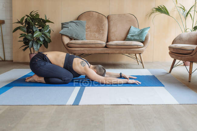 Donna dai capelli corti che fa yoga bambino posa in casa loft interno con molte piante verdi — Foto stock