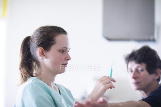 Infirmière avec seringue et une patiente femme — Photo de stock