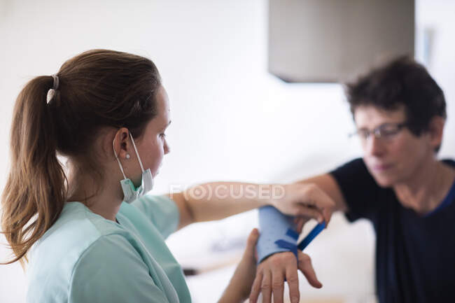 Enfermera haciendo un brazalete a una paciente mujer - foto de stock