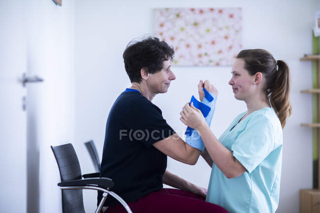 Nurse tigthing a armbracer to a patient female — Stock Photo