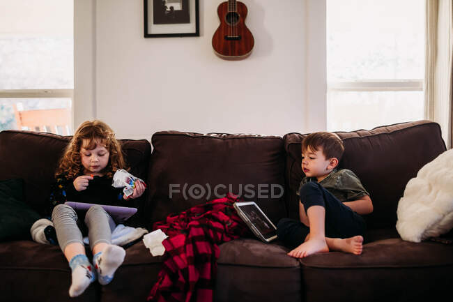 Hermana joven y hermano en casa enfermos de gripe en la escuela - foto de stock