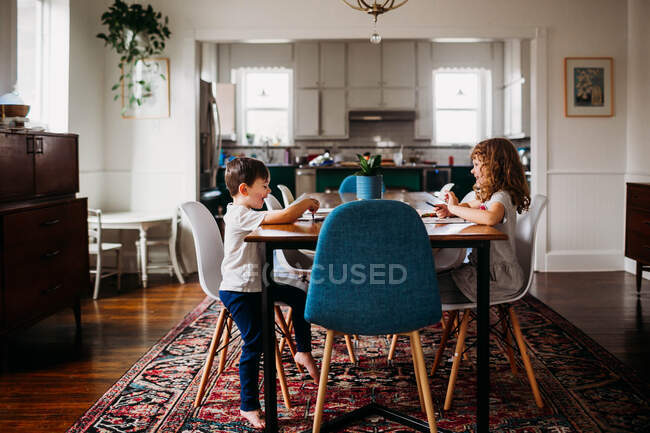 Jovens crianças sentadas na mesa de jantar fazendo artes e ofícios juntos — Fotografia de Stock