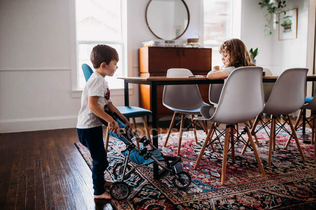Young brother showing a toy stroller to his sister — Stock Photo