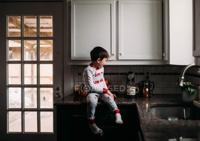 Niño sentado en un mostrador y haciendo café - foto de stock