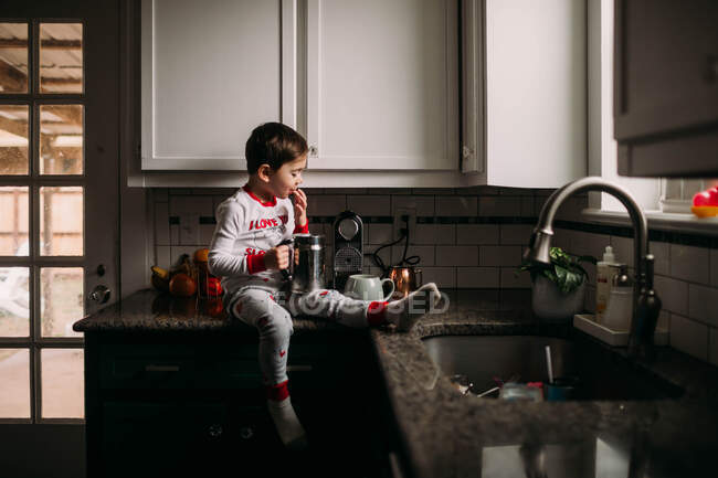 Мальчик сидит на прилавке и пьет пенное молоко. — стоковое фото