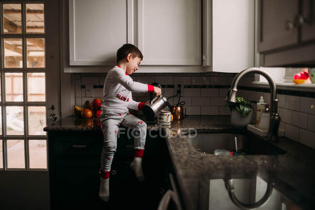 Young boy pouring frothy milk into the coffee cup — Stock Photo