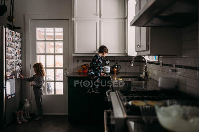 Niño y niña ayudando en la cocina durante el desayuno - foto de stock