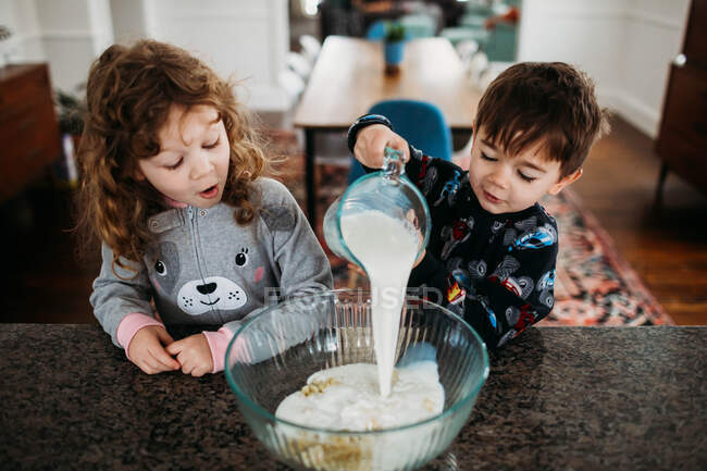 Young brother and sister wearing pajamas and making breakfast together — Stock Photo