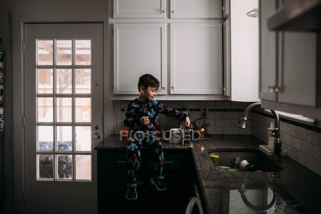 Niño en la cocina aprendiendo a hacer café por la mañana - foto de stock