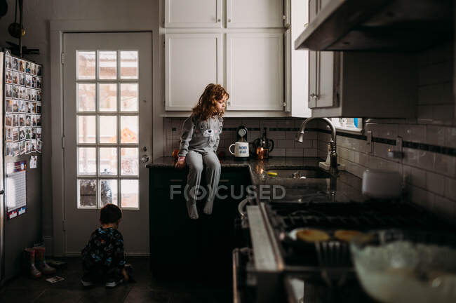 Девочка и мальчик носят пижамы и помогают готовить завтрак на кухне — стоковое фото