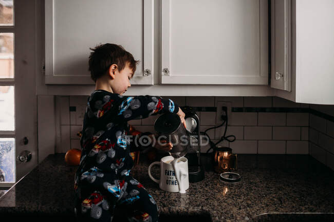 Молодий хлопчик виливає молоко в чашку кави — стокове фото