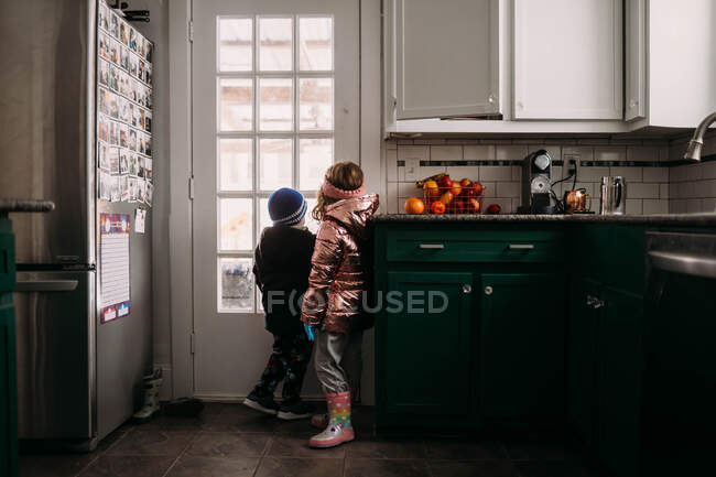 Young brother and sister wearing jackets waiting to go outside — Stock Photo