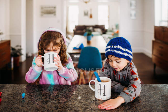 Niño y niña bebiendo chocolate caliente en un frío día de invierno - foto de stock