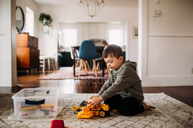 Toddler boy sitting and putting together a toy tractor — Stock Photo