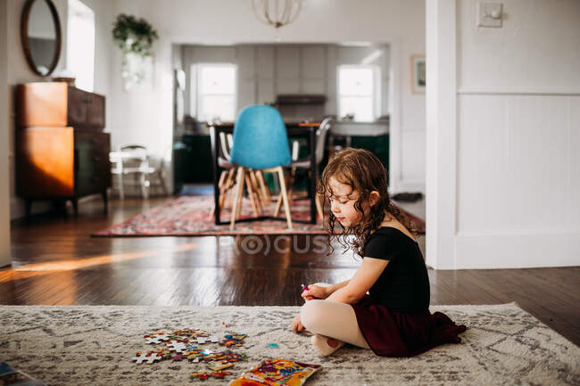 Young girl in ballet clothes sitting on a floor and doing puzzle — Stock Photo