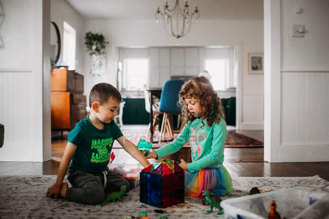 Bruder und Schwester spielen mit Magnetfliesen im Wohnzimmer — Stockfoto