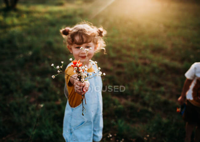 Giovane ragazza che tiene un mazzo di fiori selvatici — Foto stock