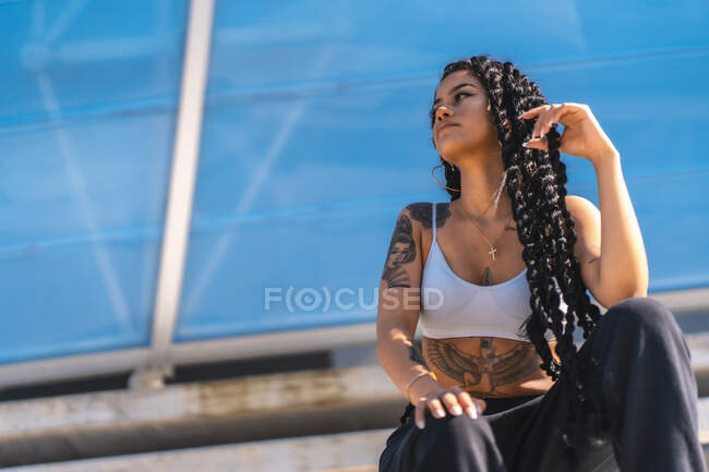 Jovem menina negra com tatuagens, armadilha dançarina sentado olhando para a esquerda — Fotografia de Stock