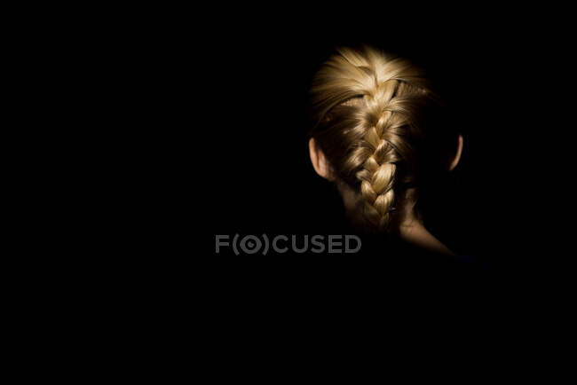 Blonde fille tresse dans la lumière avec fond sombre — Photo de stock